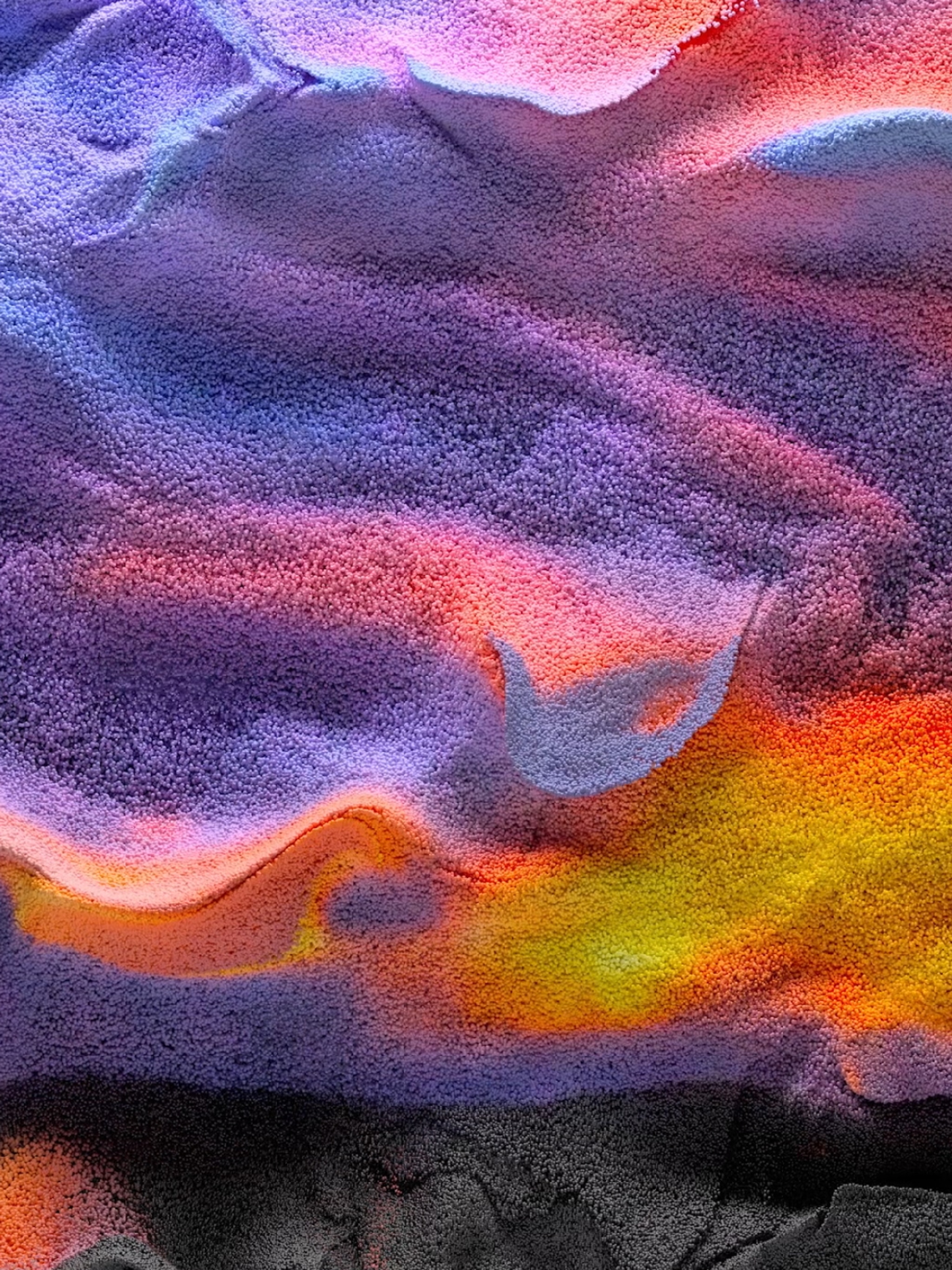 An abstract image that resembles a sandy landscape in the pink, purple, and orange hues of a desert sunset