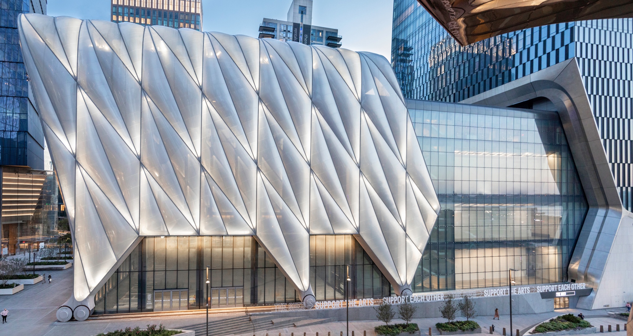 The Shed's north-facing façade at dusk, with the building's movable shell lit and glowing from within