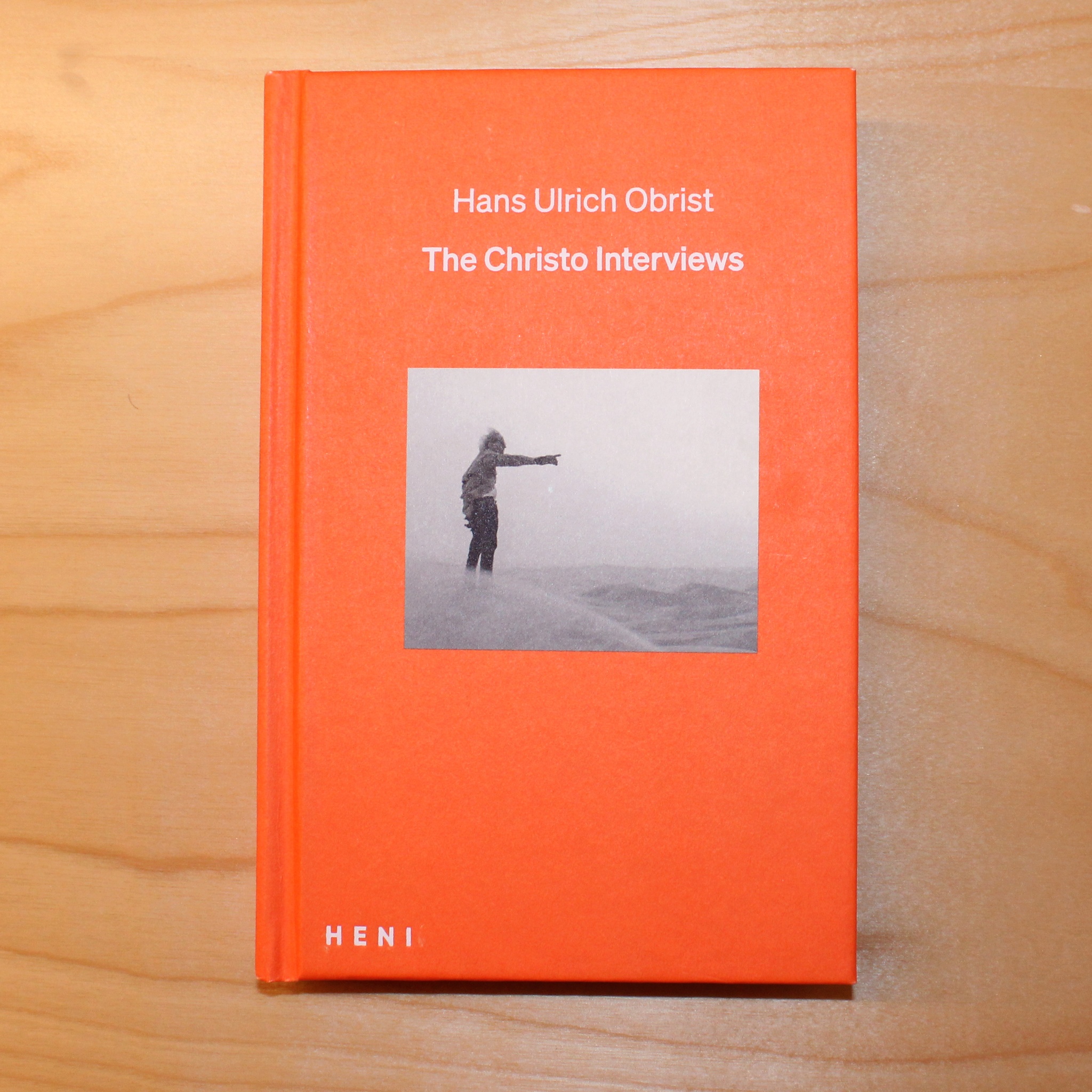 An orange book with an image of a man outstretching his arm. The title reads The Christo Interviews.