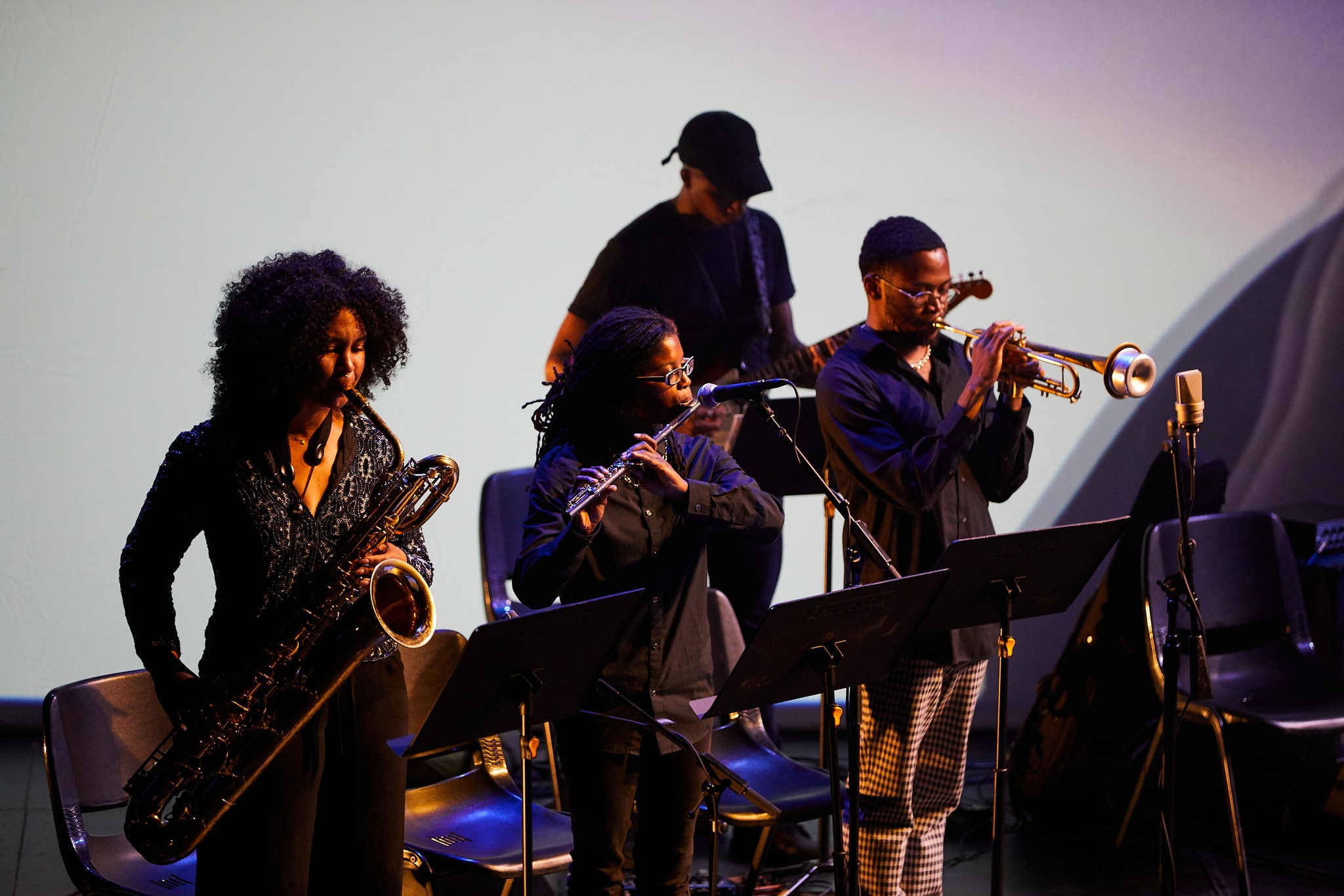 Four musicians standing on stage while playing.