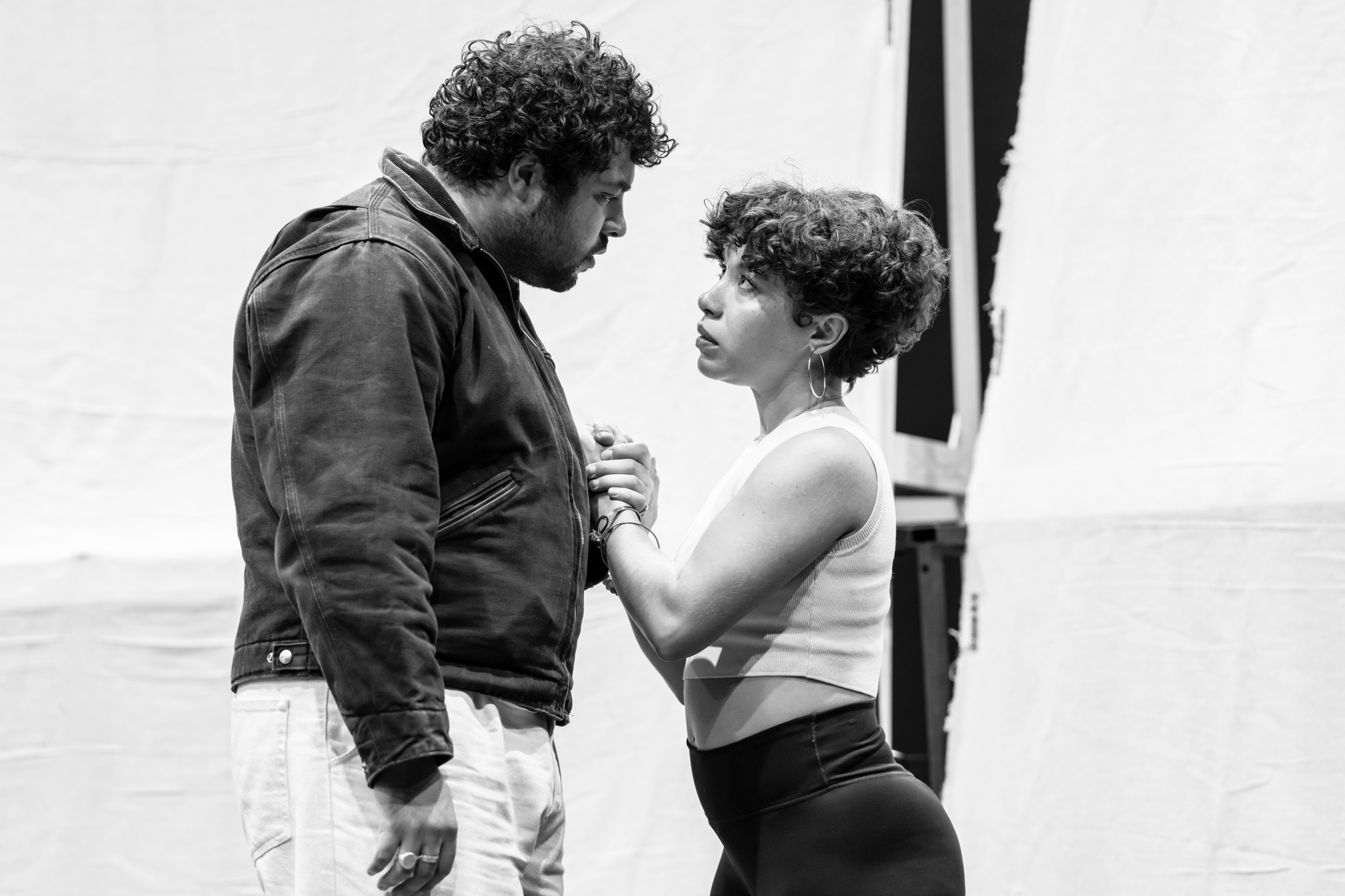 Actors Dylan Corbett-Bader and Saffron Coomber rehearse an intimate moment. They stand close looking into each others' eyes and holding hands.