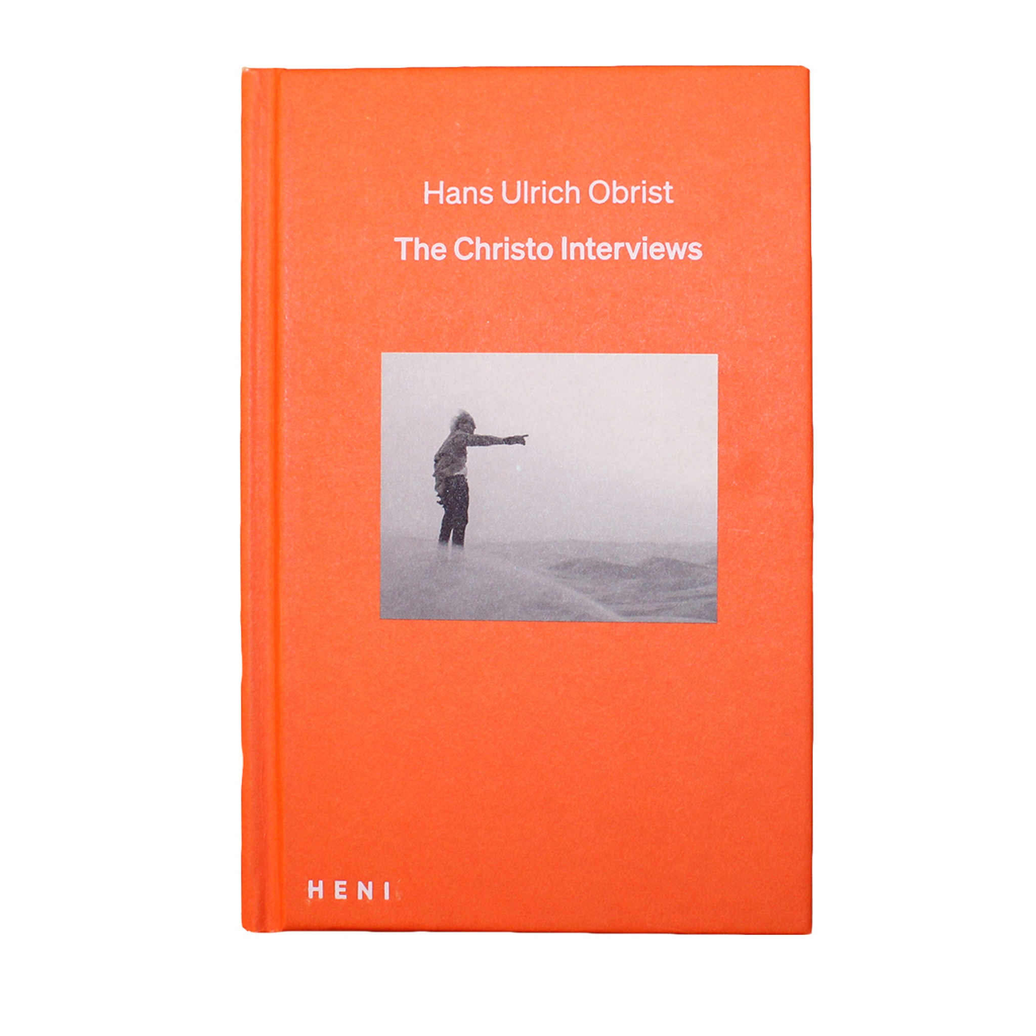 An orange book with an image of a man outstretching his arm. The title reads The Christo Interviews.