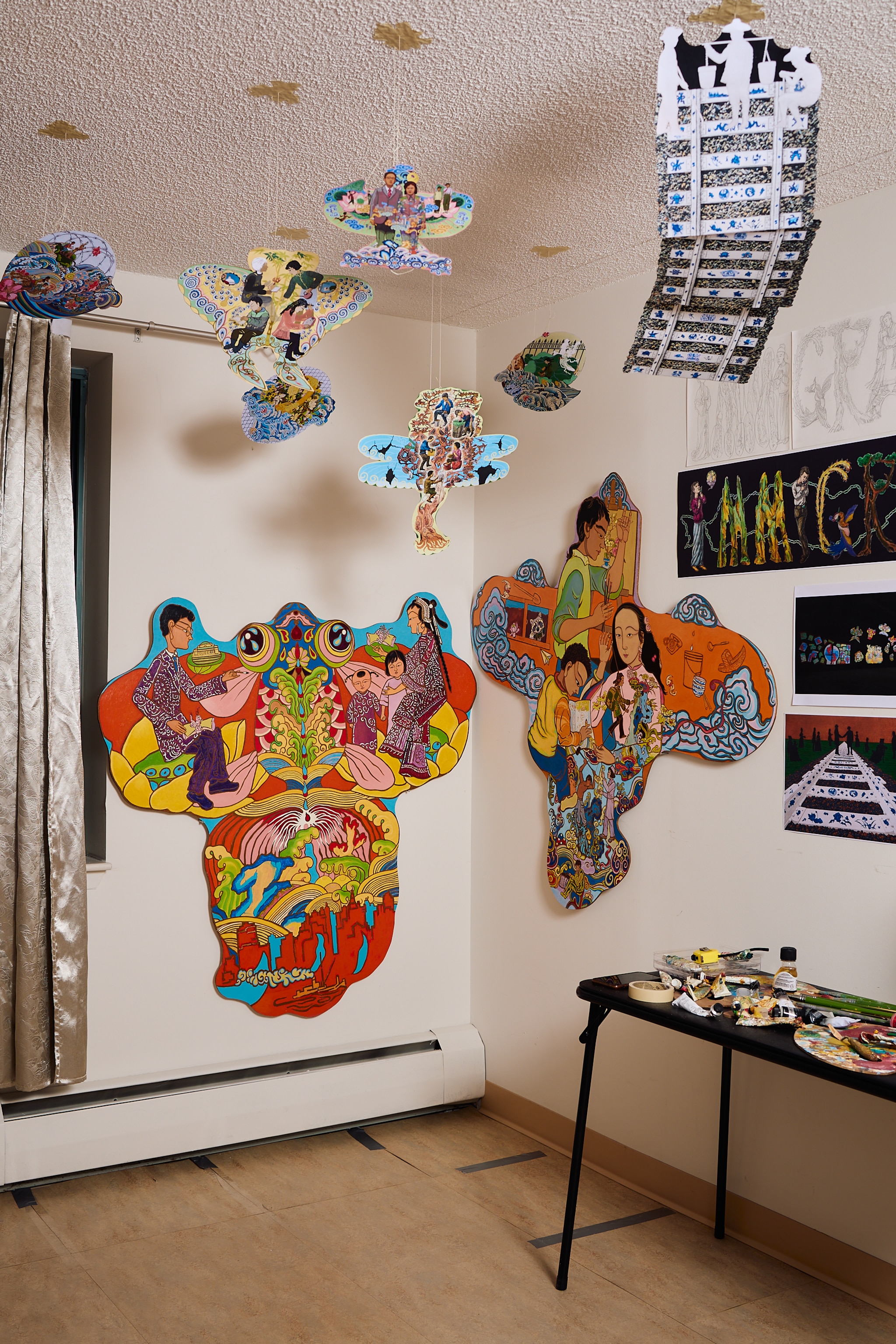 A corner of Lily Honglei's studio space is decorated with paintings in the shape of Chinese kites that hang on the walls and from wires from the ceiling. 