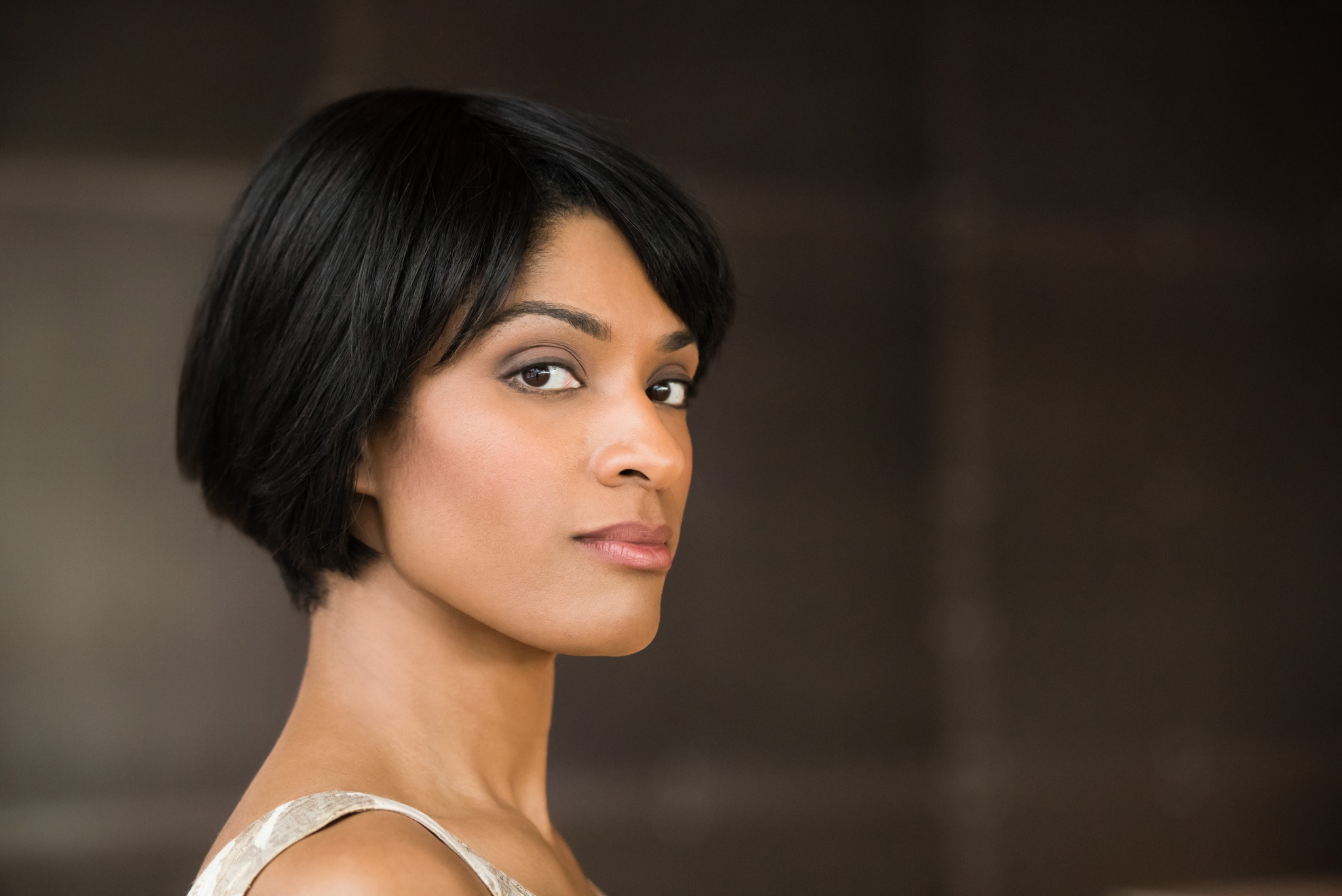 A woman seen in profile turning her head to look at the camera. She has short hair cut in an angular style to the top of her chin.