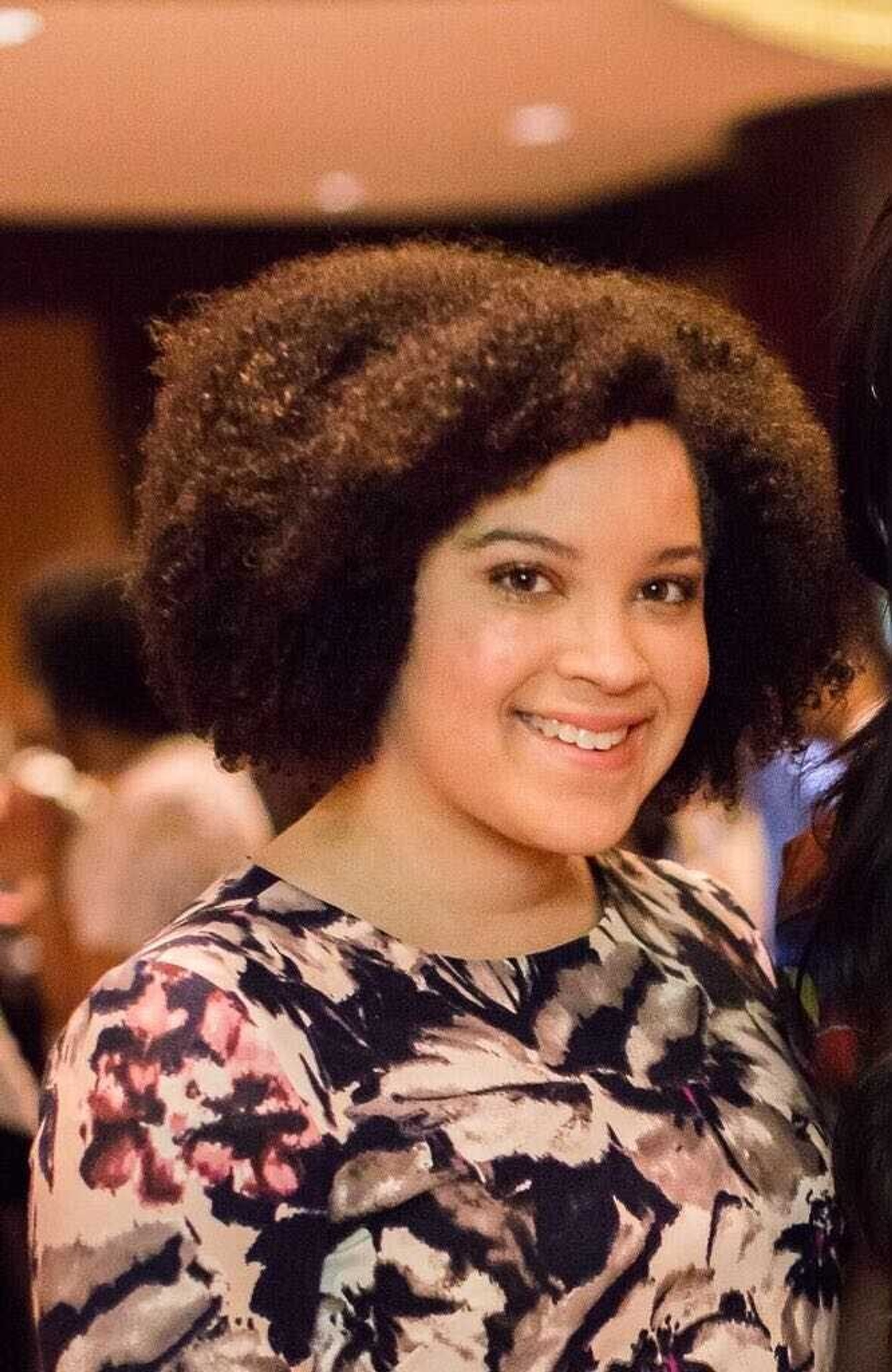 A photo of Shed assistant curator Adeze Wilford in three-quarters view. She is wearing a floral-print blouse.