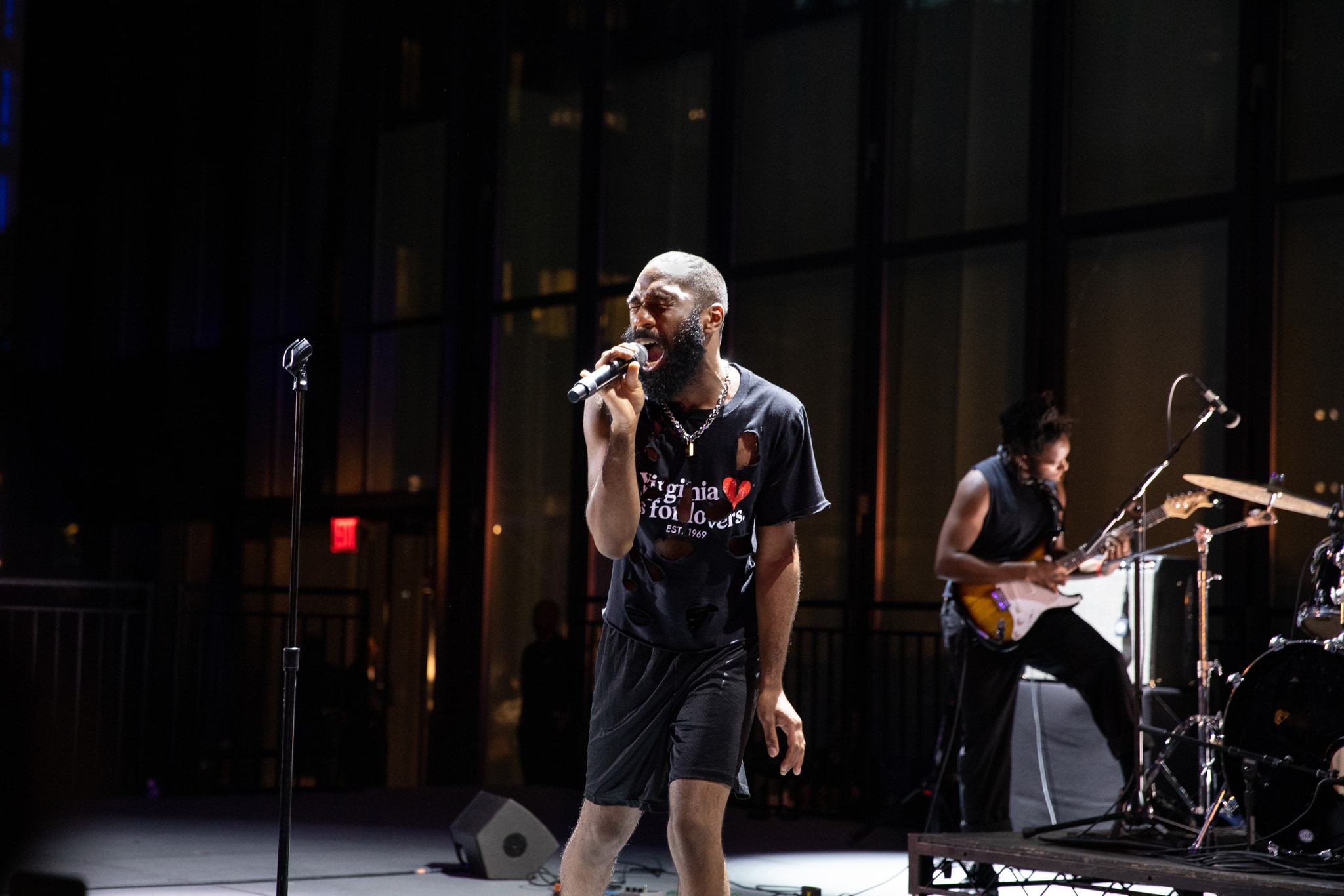 Man singing into mic on dramatically lit stage.