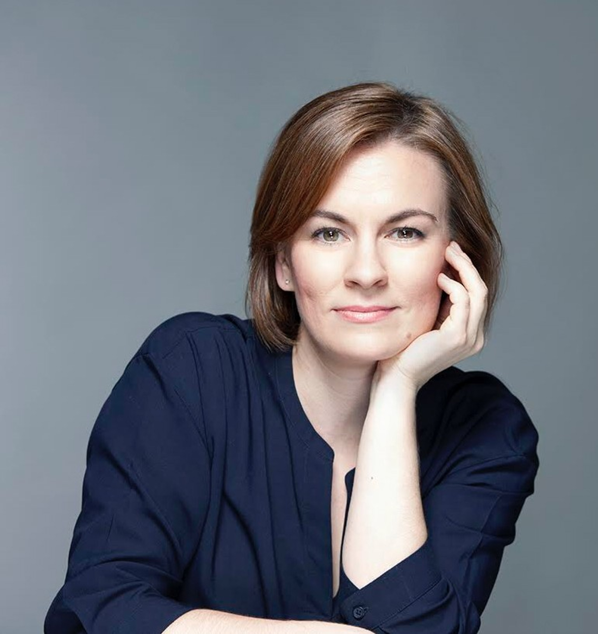 The conductor Daniela Candillari, a white woman with chin-length light brown hair. She props her chin on one hand and wears a navy blue blouse.