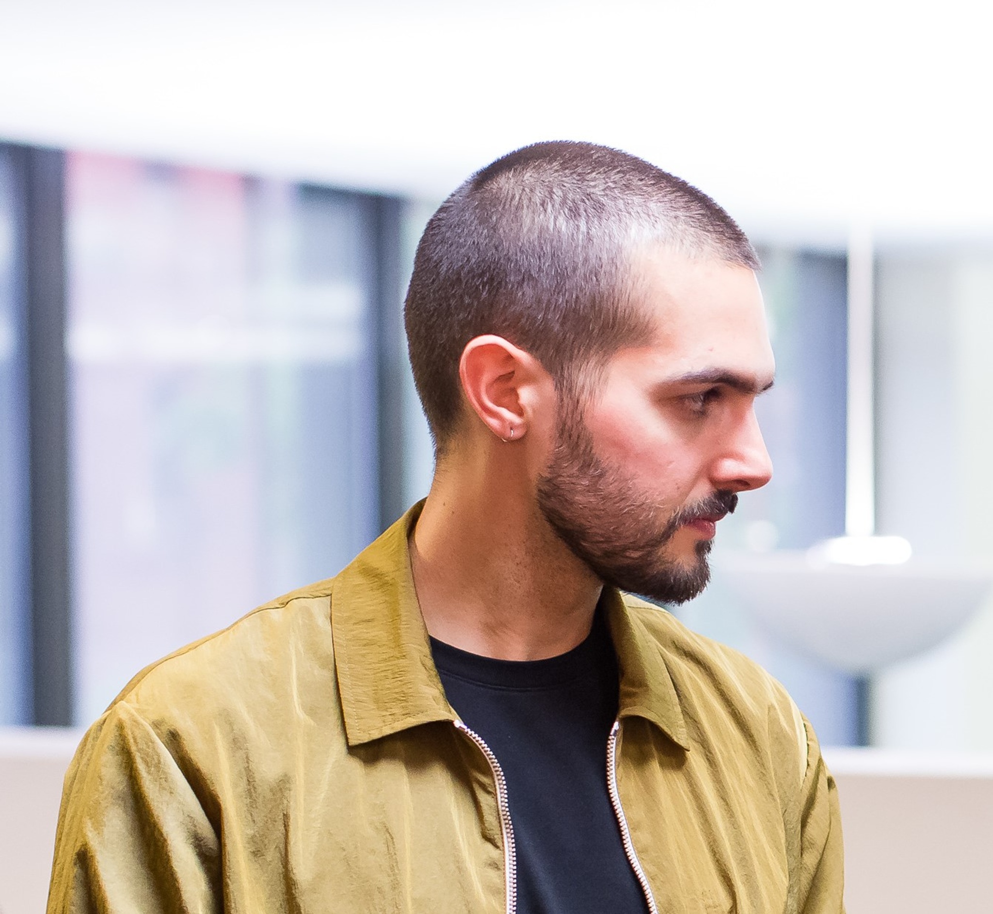 A photo of Eric Guy Booker taken from the side. Booker wears a tan jacket and has a beard and buzzed hair. 