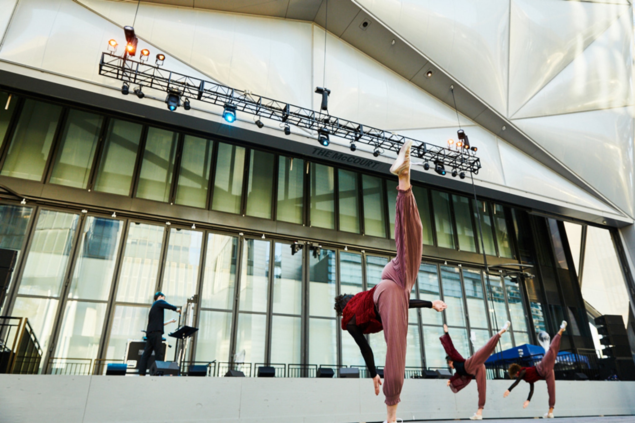 Three dancers in motion on an outdoor stage.