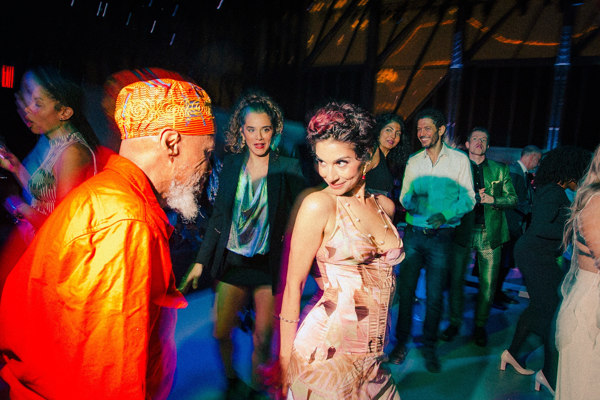 Gala guests in colorful outfits dance together on the dance floor.