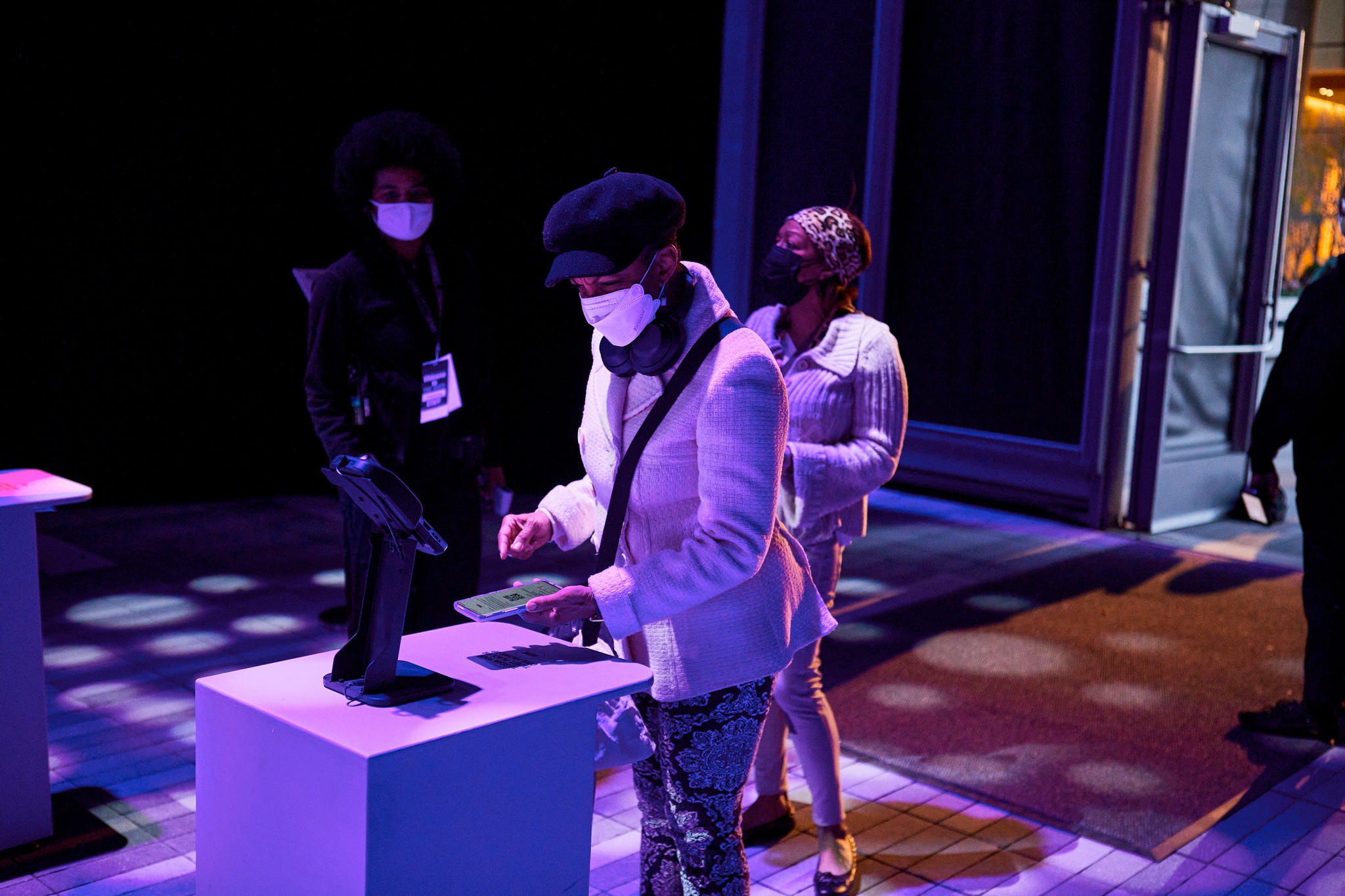 An audience member wearing a hat, face mask, and sweater scans their digital ticket at the entrance to The McCourt.