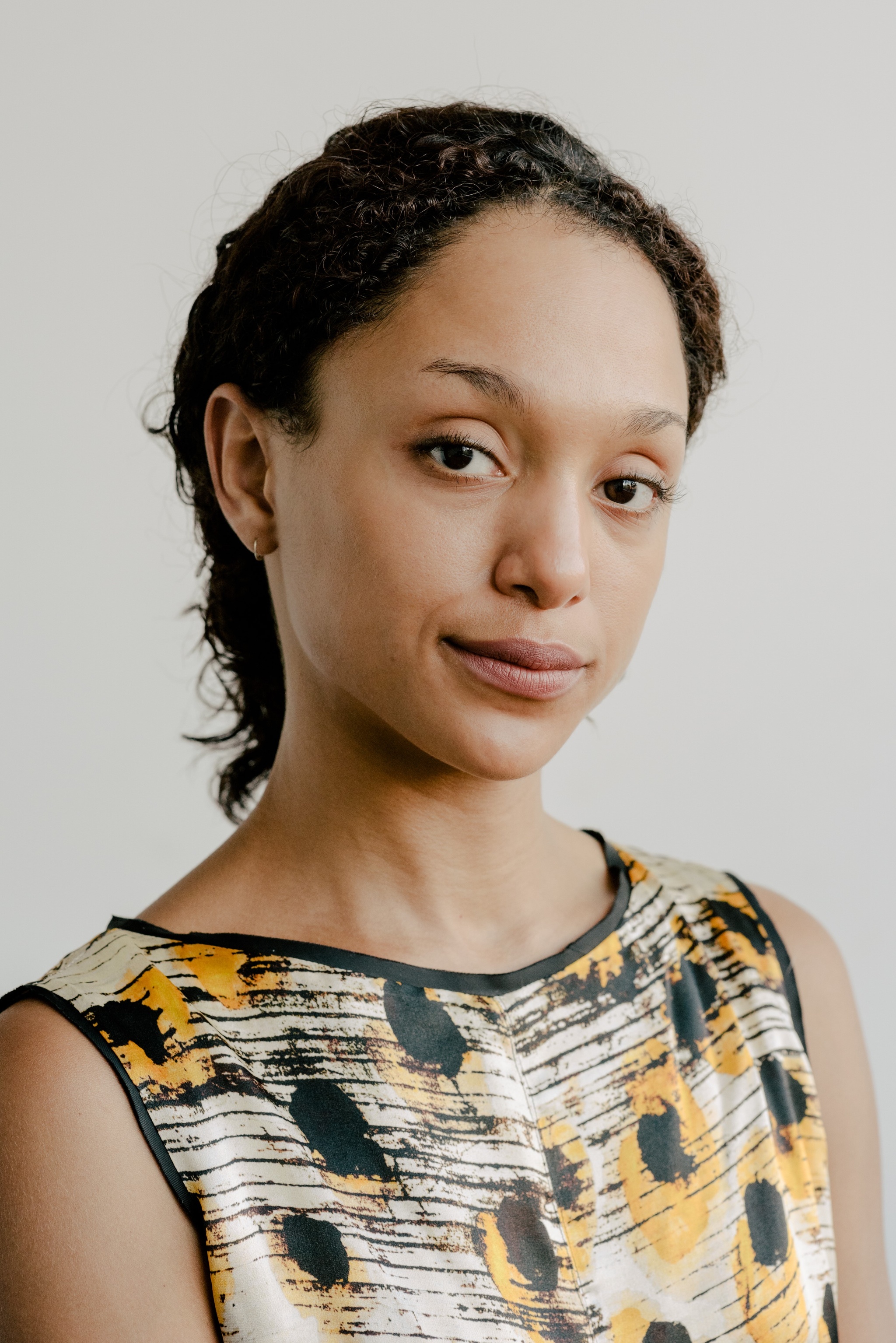 A photo of curator and writer Legacy Russell. She has her hair pulled back and has turned her head slightly to the right, and her right eyebrow appears to be slightly raised. 