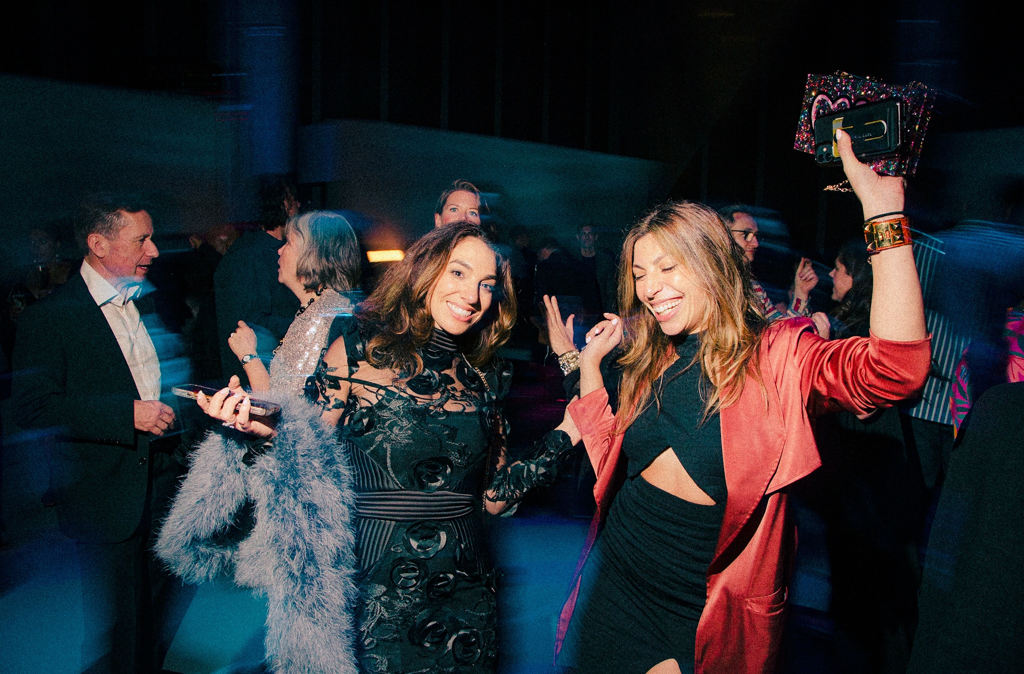 Gala guests dance with their hands in the air, smiling. 