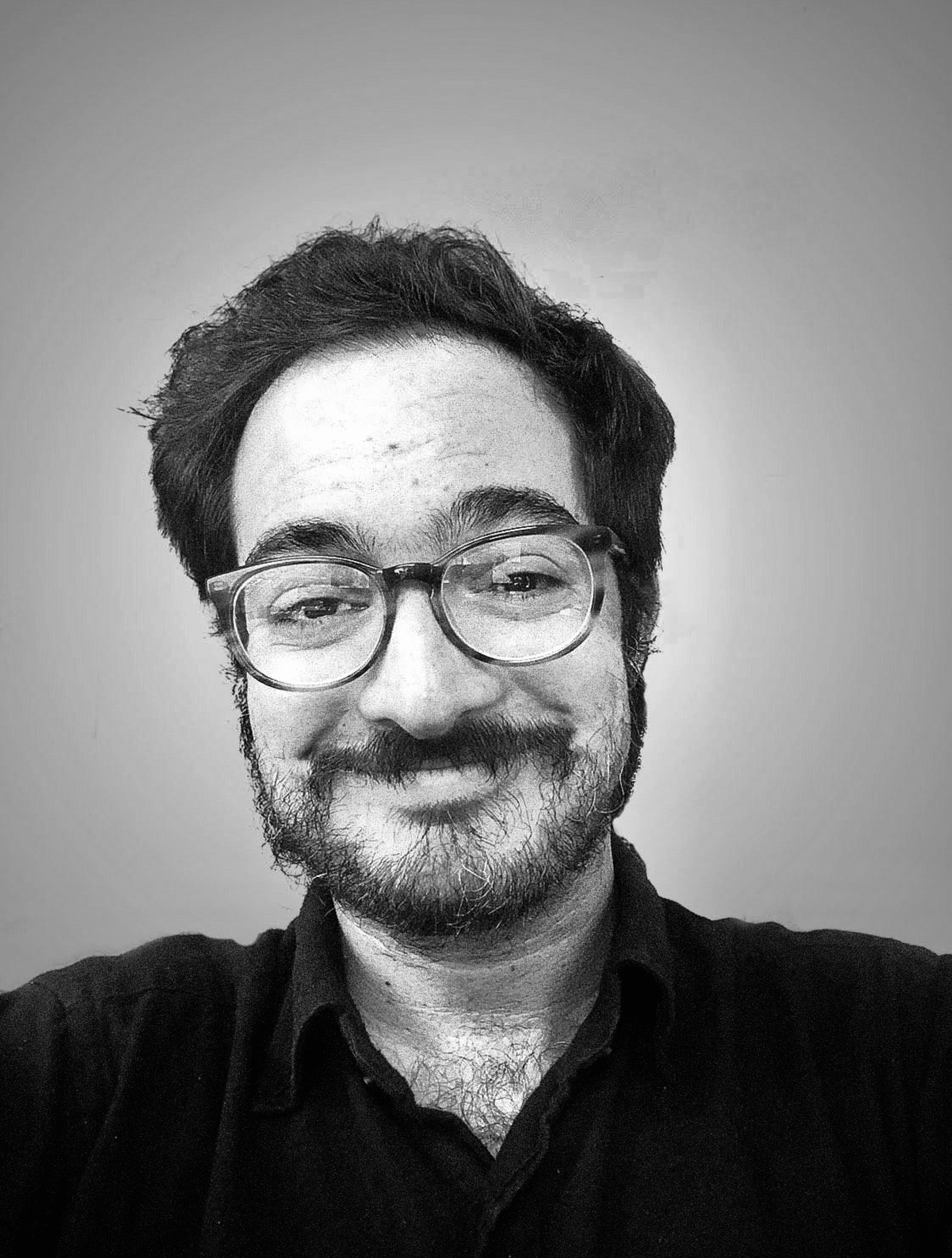 A black-and-white photo of José F. Rodriguez, who wears glasses and smiles at the camera, 