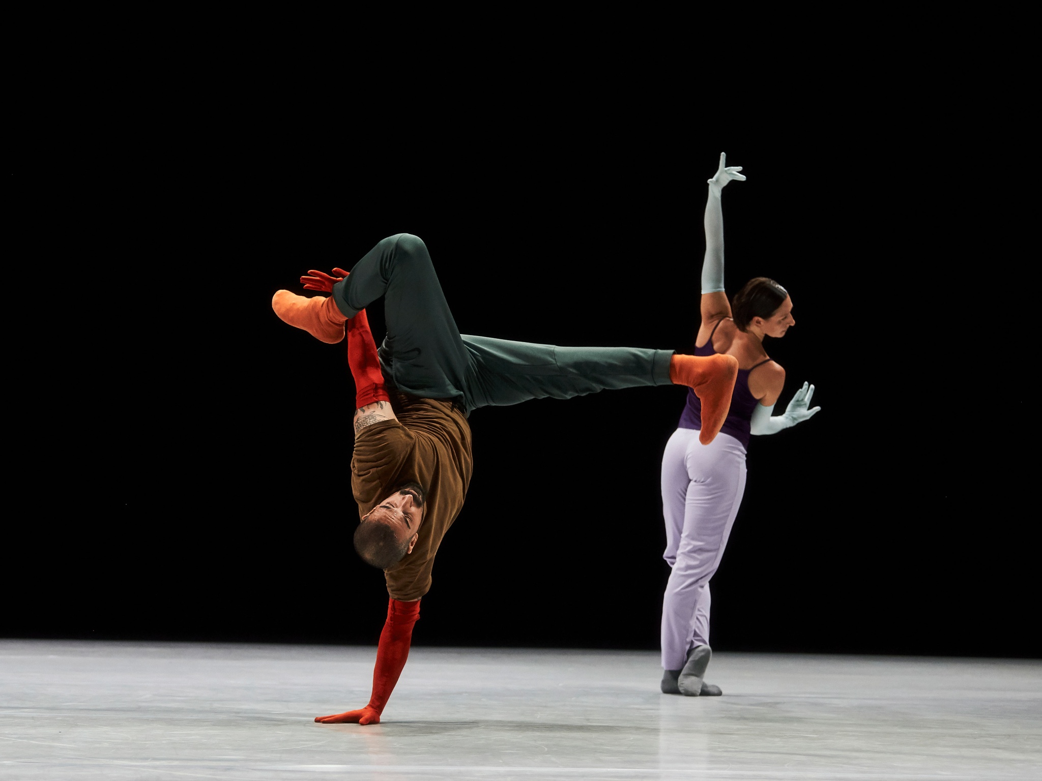 Two dancers in motion against black background