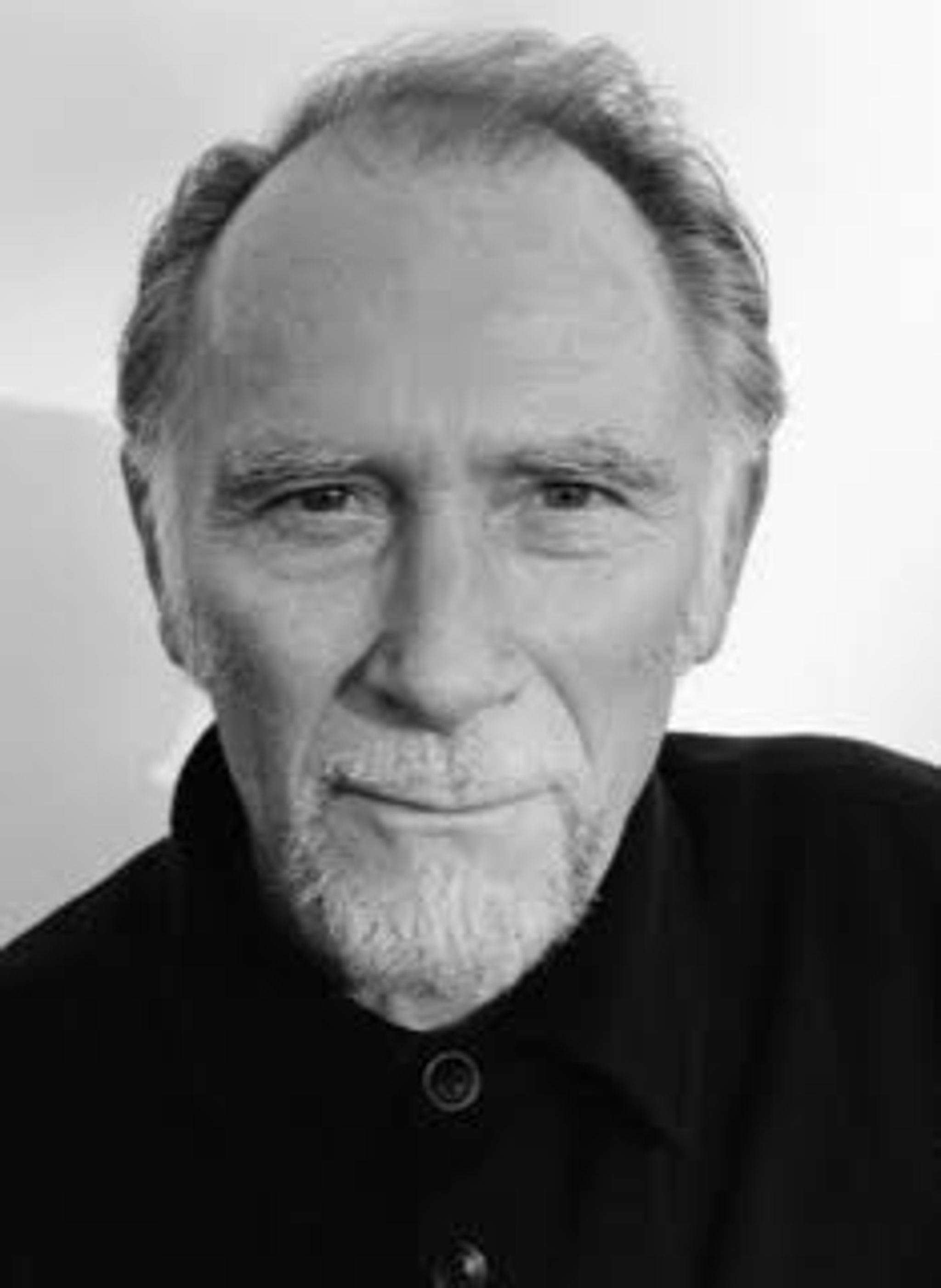 A portrait of actor Danny Webb, a white man with graying salt and pepper hair and a goatee. 