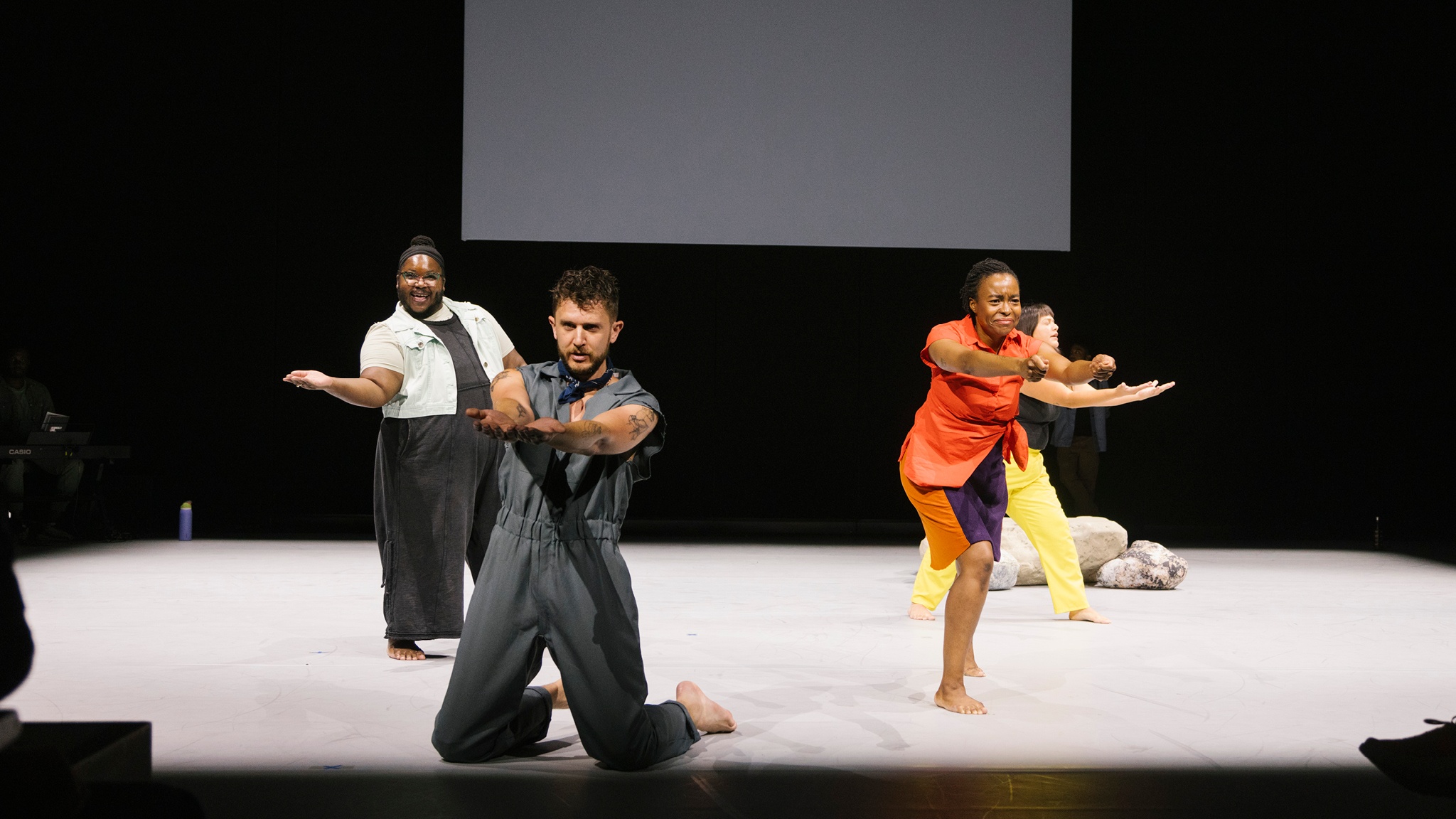 Four cast members of How to Bend Down/ How to Pick it Up reach their arms out, forearms offered up, all in different styles. One performer kneels, another stands and gestures with just one arm, two performers lunge as they offer their arms. Photo by Ahad Subzwari/The Shed.