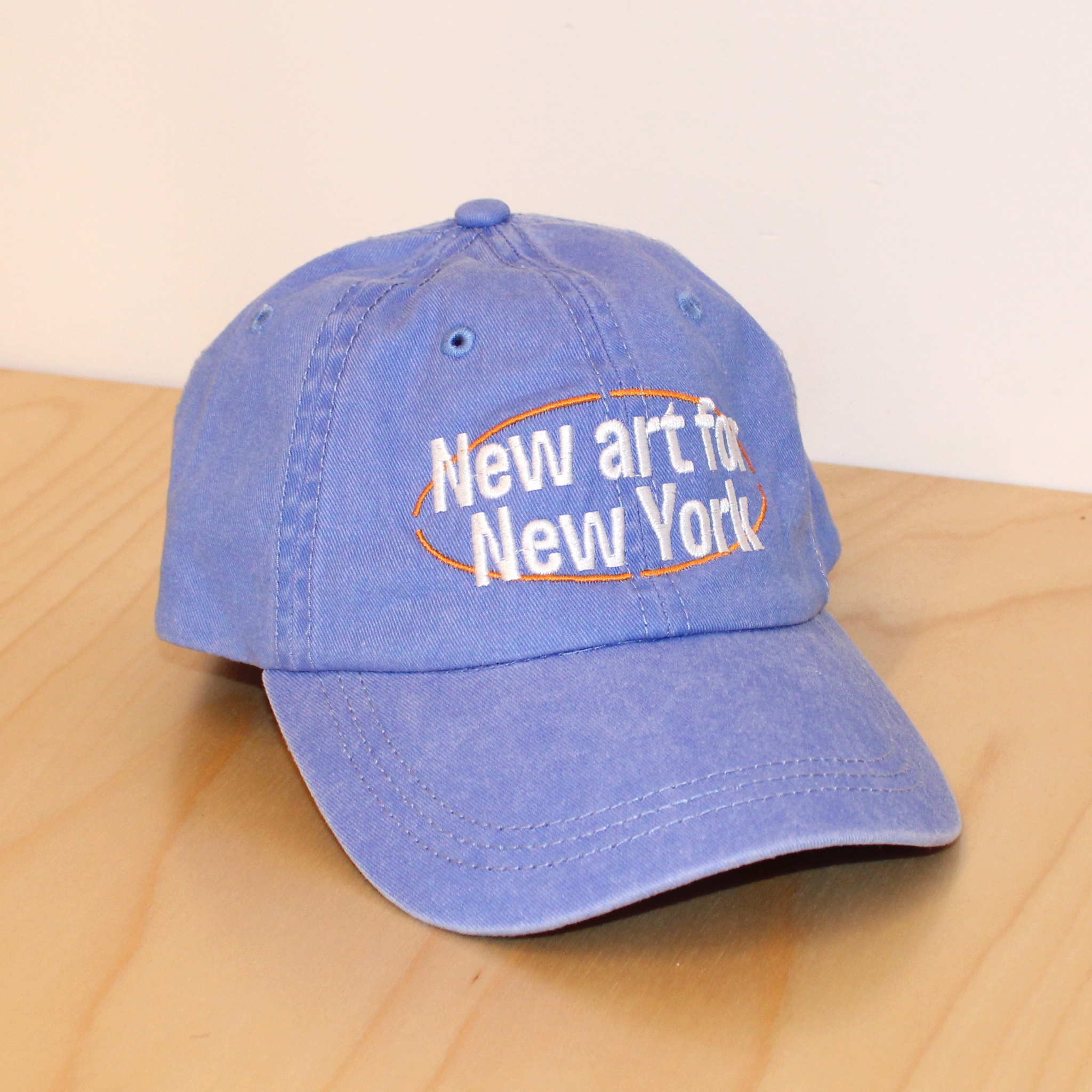 A blue canvas cap with the words New art for New York above the bill